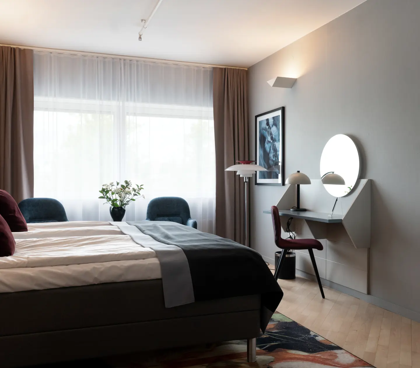 Mysigt hotellrum med dubbelsäng, fönster och skrivbord