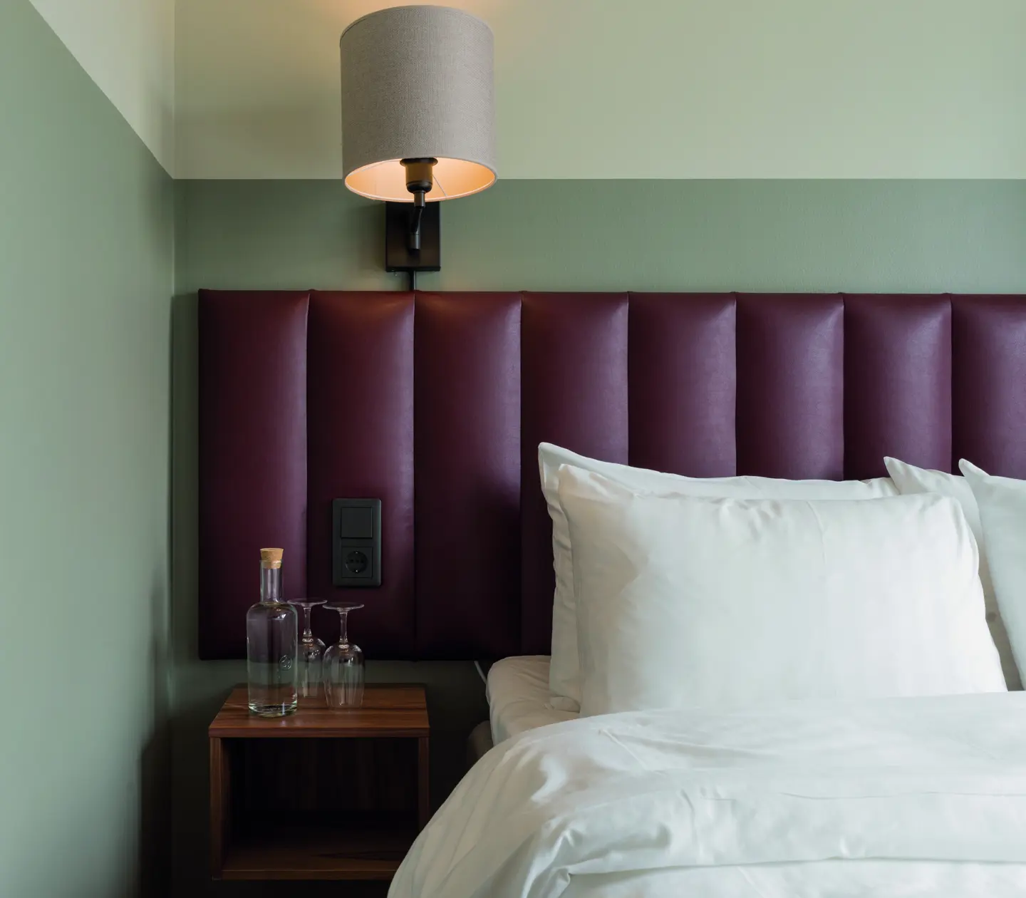 Detaljbild på en hotellsäng med röd sänggavel
