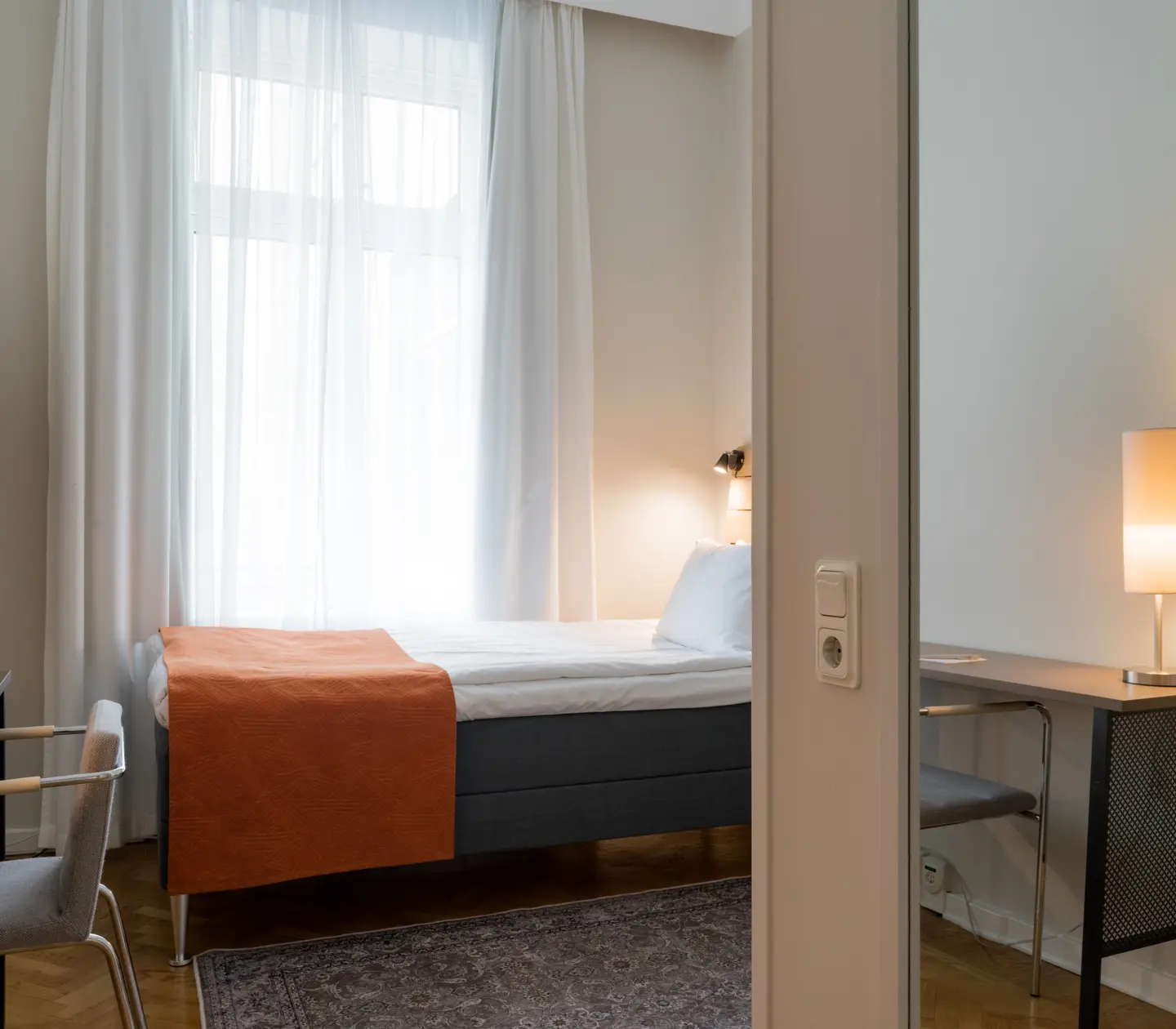 Mysigt hotellrum med enkelsäng, skrivbord och fönster
