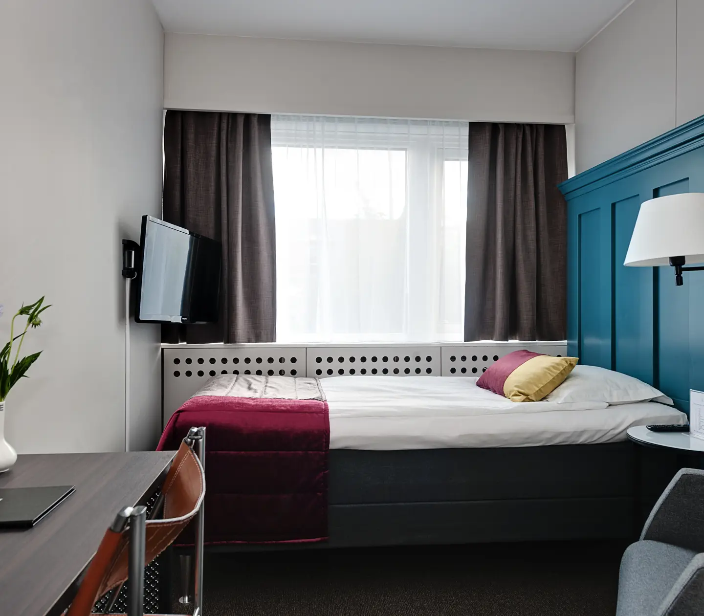 Färgglatt hotellrum med enkelsäng med stor blå sänggavel
