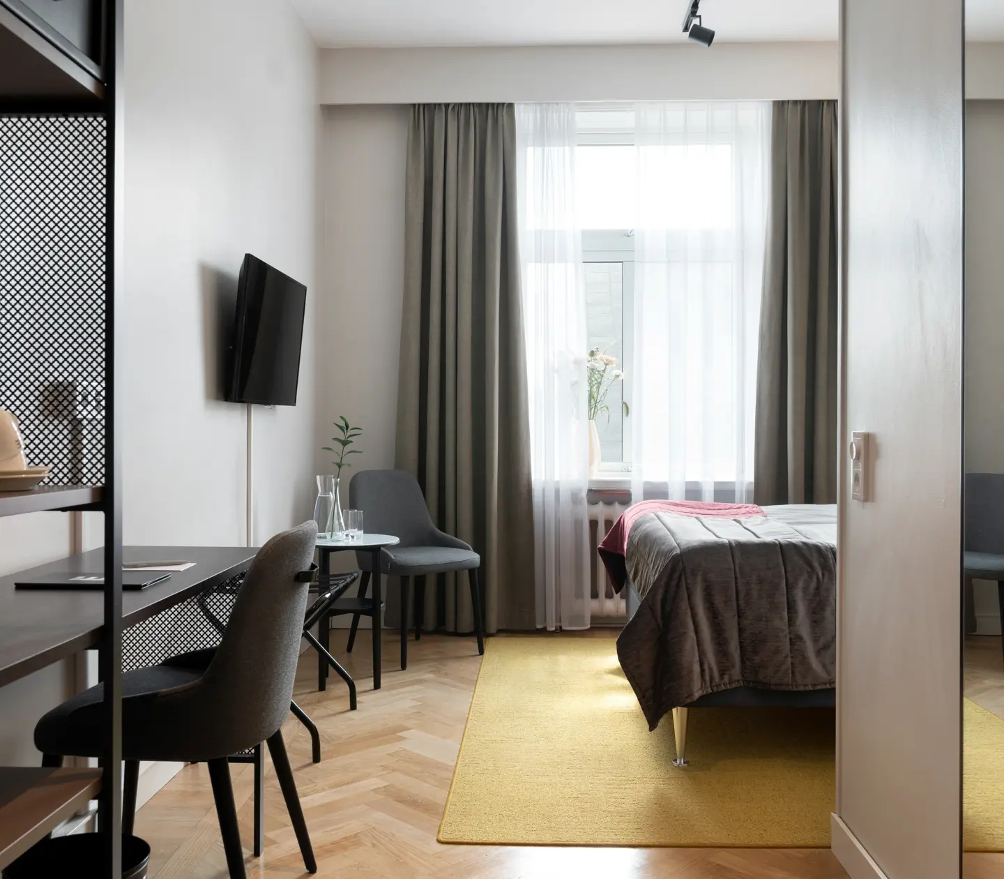 Hotellrum med skrivbord, fåtölj, tv och fönster