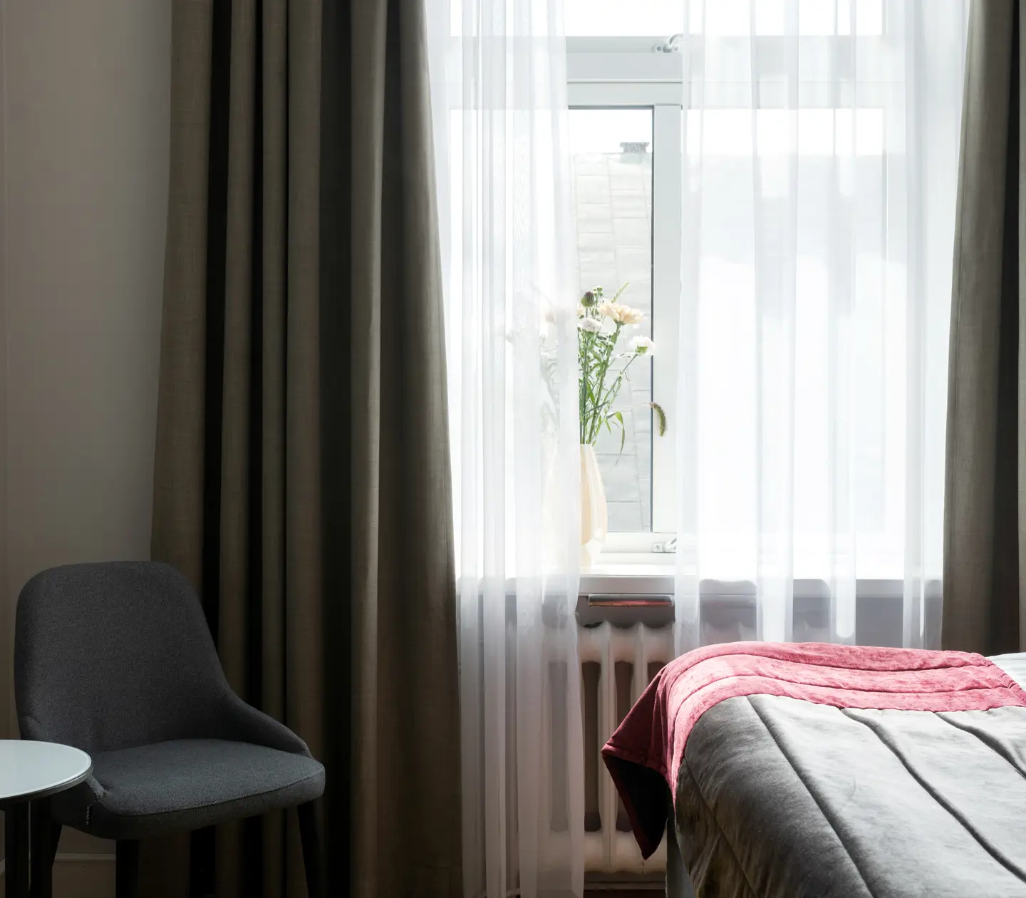 Hotellrum med fönster och fåtölj