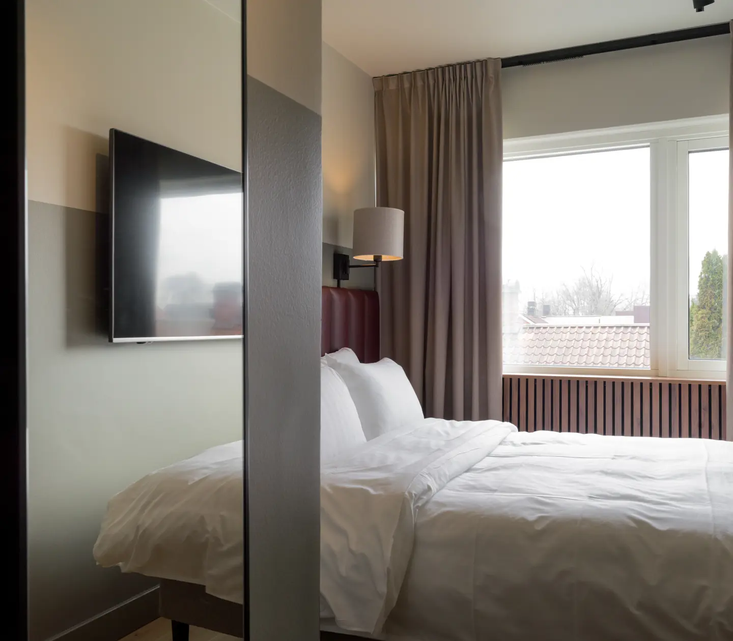 Hotellrum med dubbelsäng, spegel och fönster