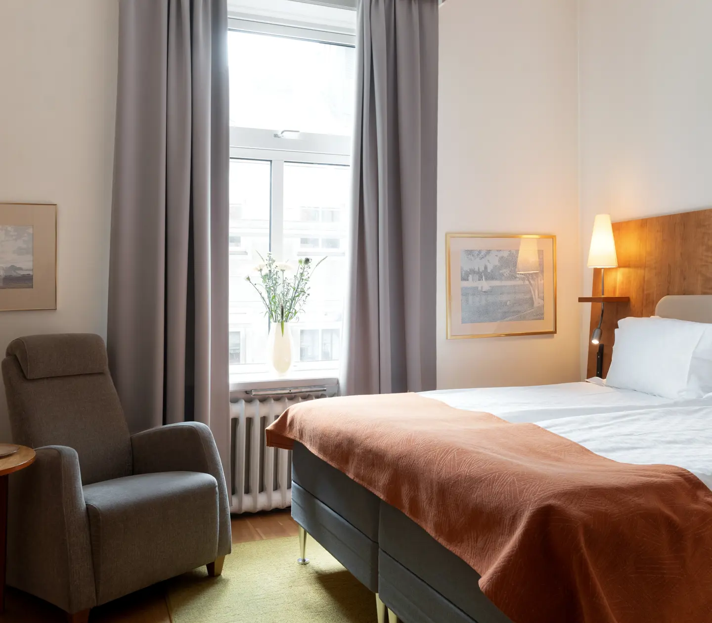 Mysigt hotellrum med dubbelsäng, fåtölj och fönster