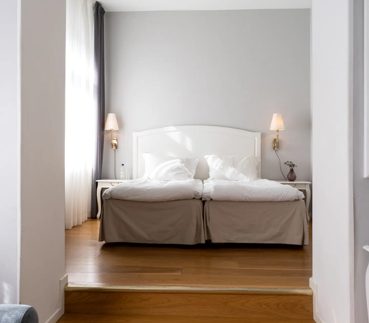 Ljust hotellrum med dubbelsäng och sänglampor