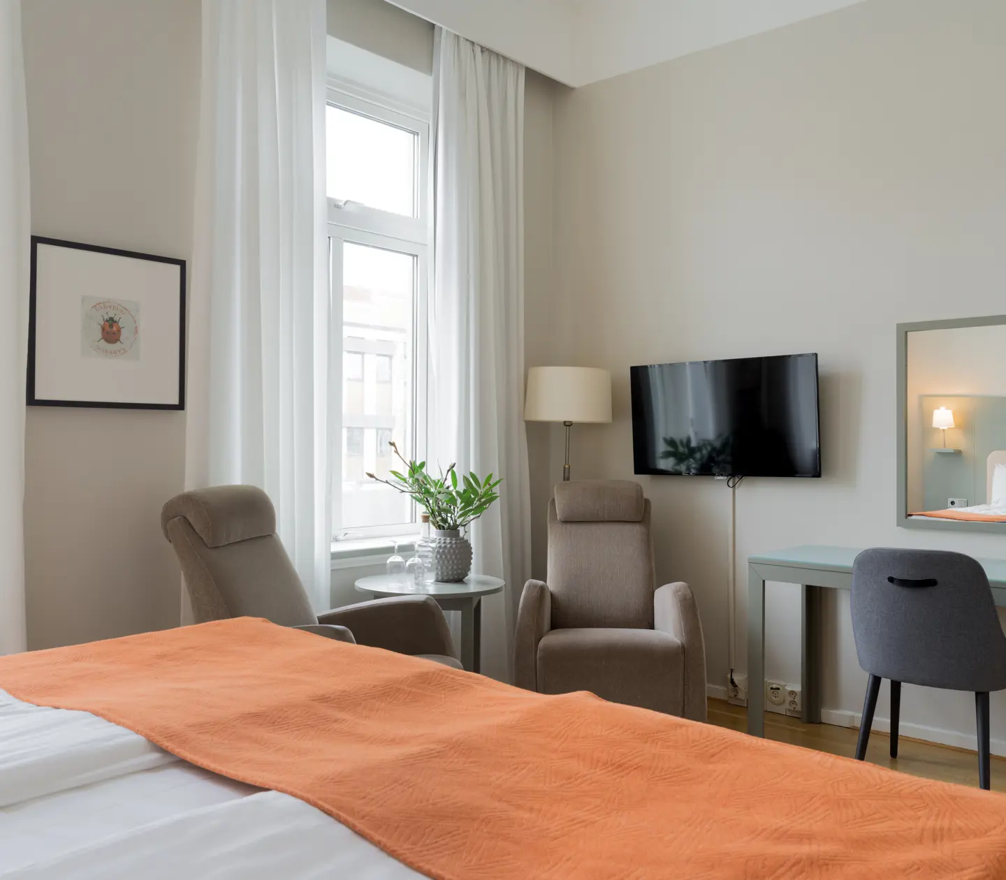 Mysigt hotellrum med fåtöljer, skrivbord och tv
