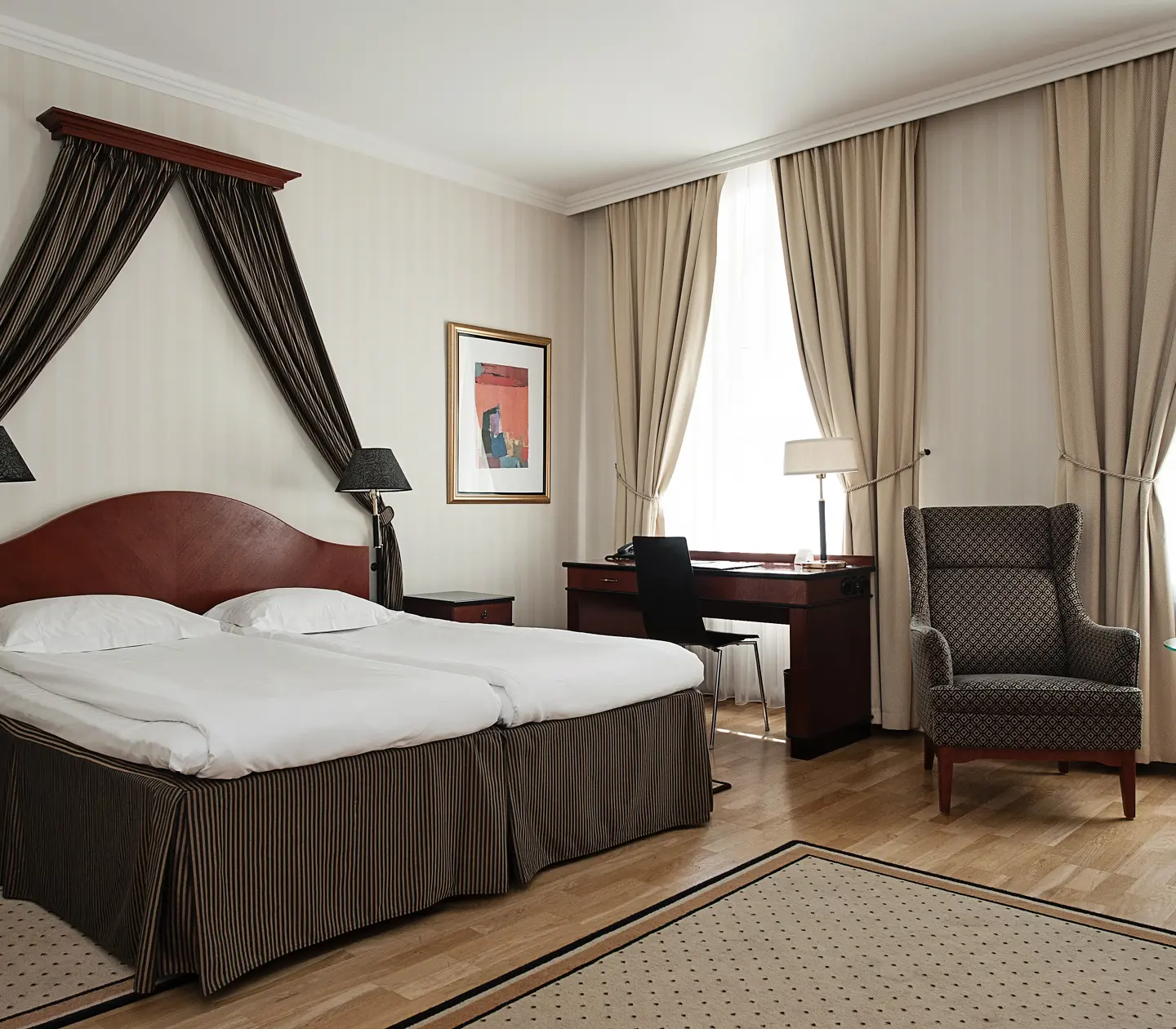 Hotellrum med dubbelsäng, skrivbord och gardiner