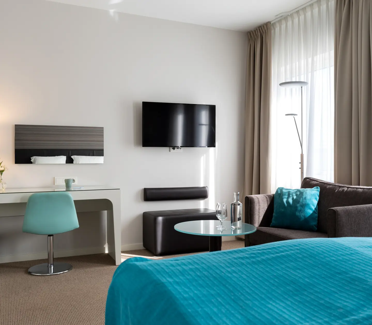 Hotellrum med dubbelsäng, skrivbord, fåtölj och tv