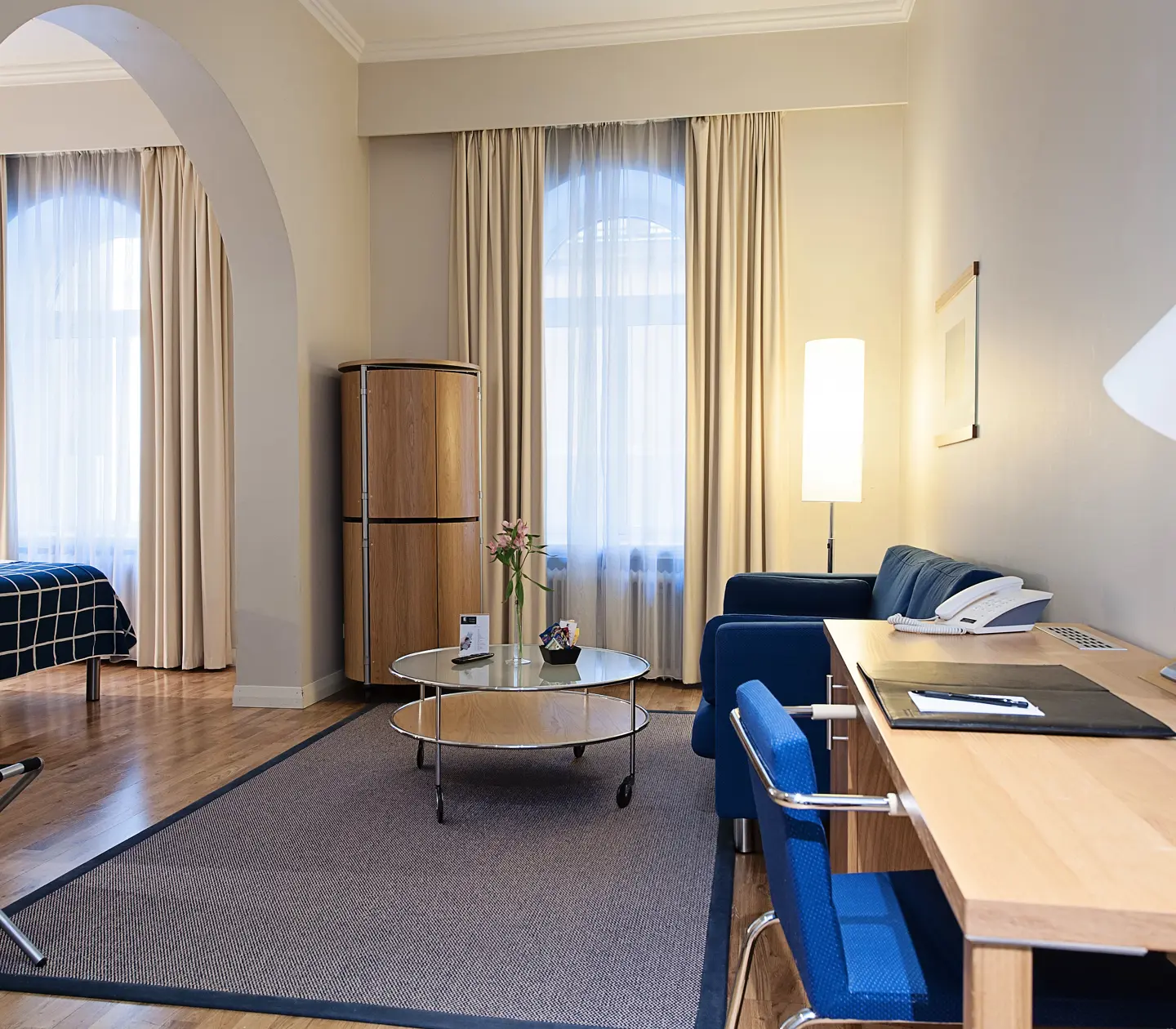 Ljust hotellrum med soffa, skrivbord och fönster