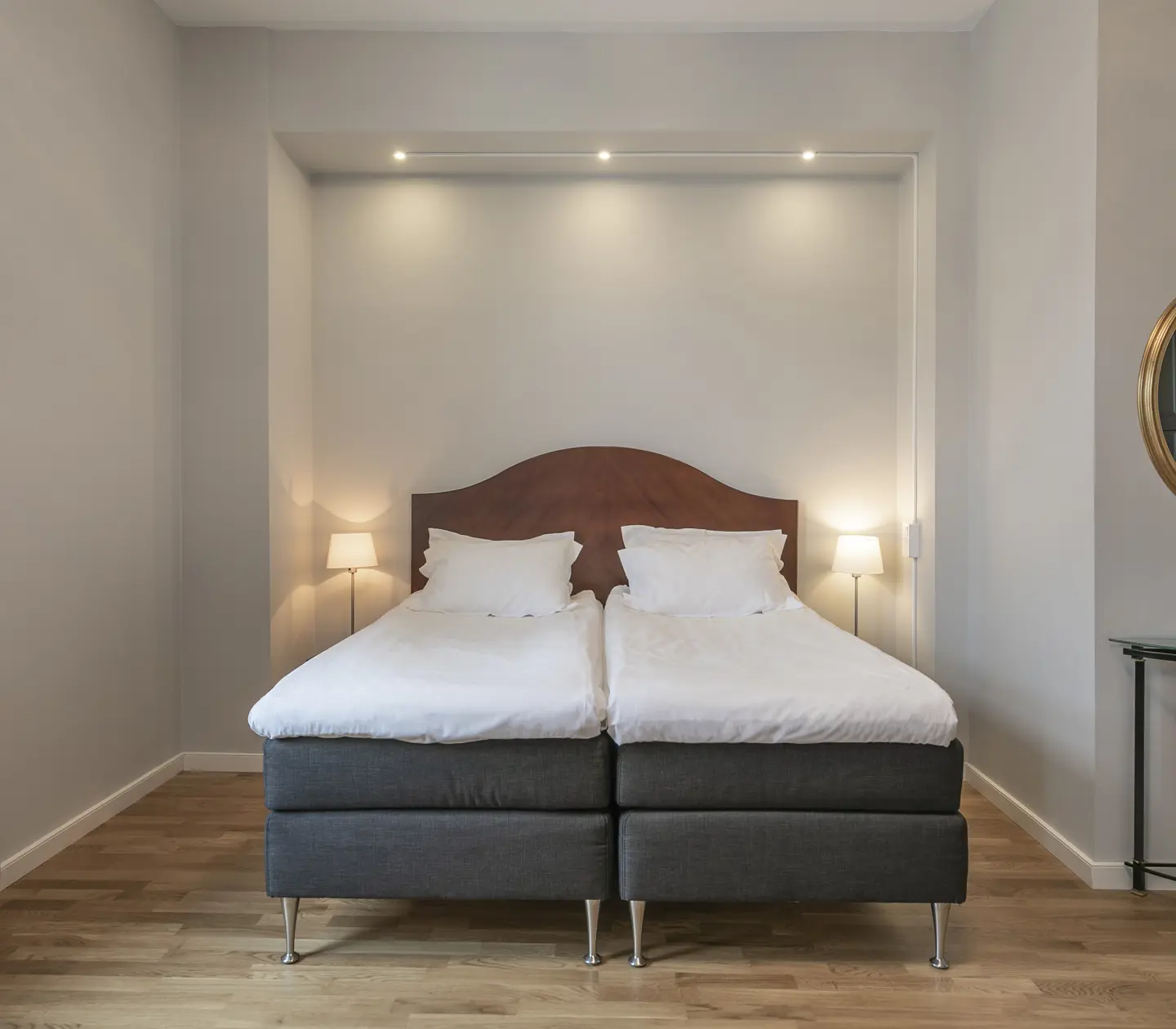 Hotellrum med dubbelsäng i ljusram och spegel