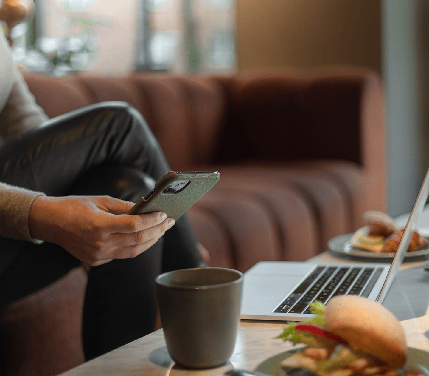 En person sitter med sin dator och tar en fika