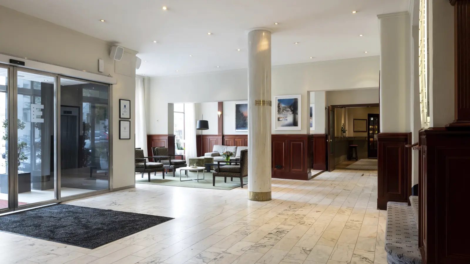 Hotellobby med marmorgolv, sittgrupp och stora fönster, som skapar en ljus och öppen atmosfär.