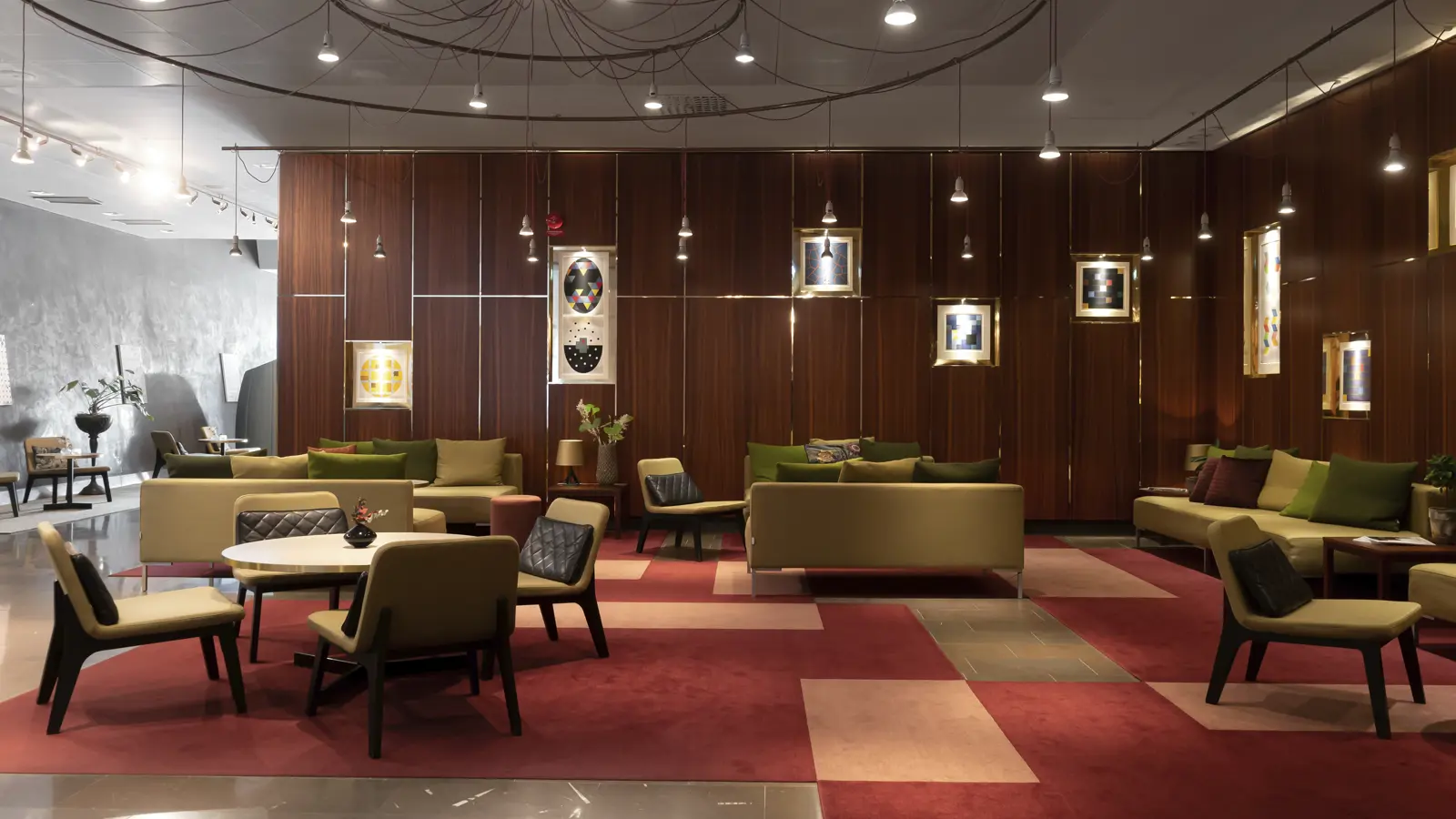 Eleganta sittmöbler i modernt hotellobby med designbelysning och konstverk på väggarna.