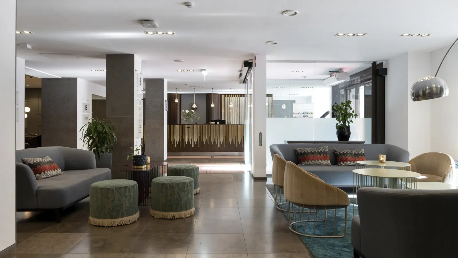 Modern hotellobby med eleganta sittmöbler, belysning och reception i bakgrunden.