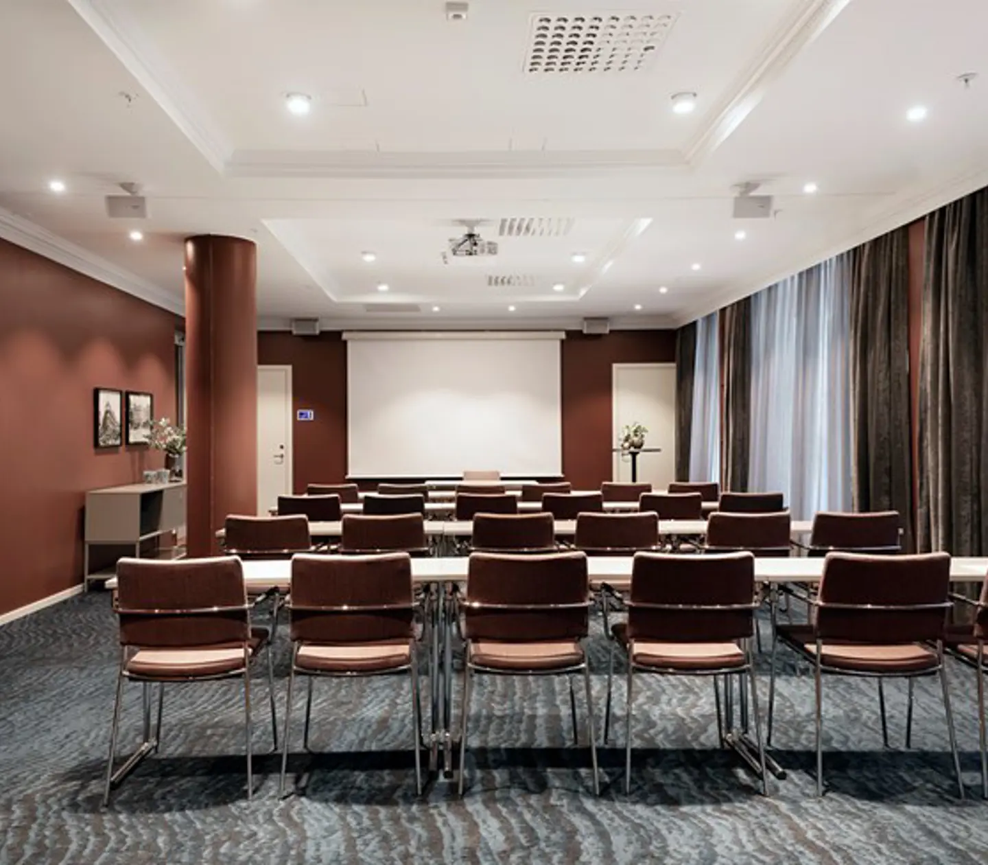 Konferensrum med skolsittning, grått golv, bruna väggar