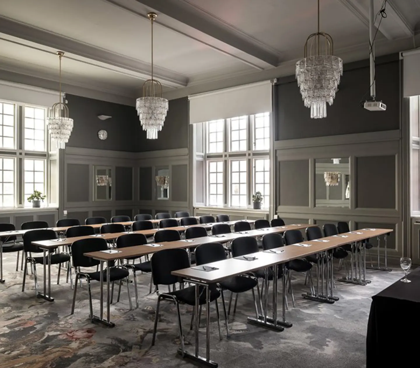 Konferensrum med många stolar, kristallkronor och fönster
